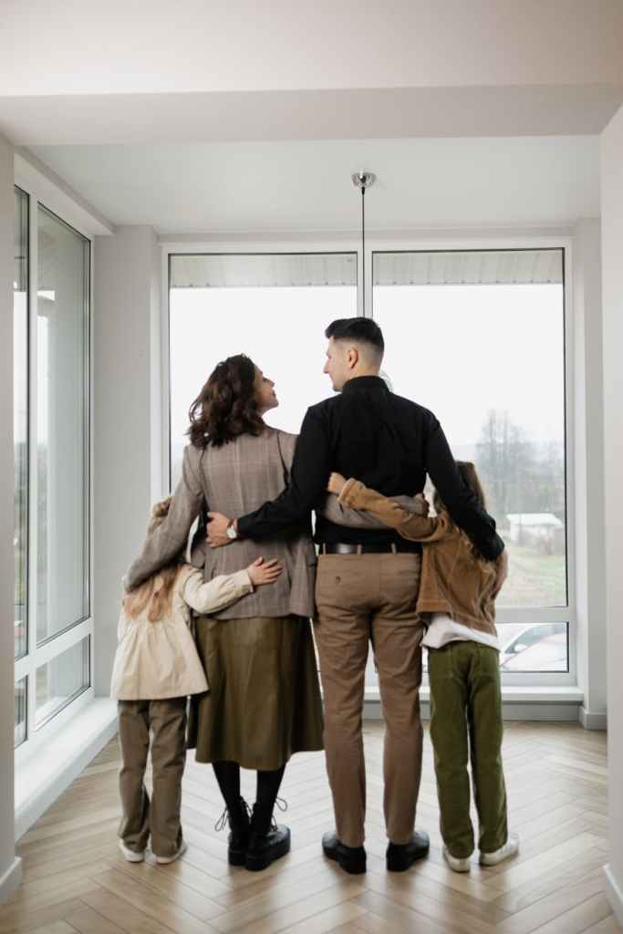 a family standing near the glass windows of the house