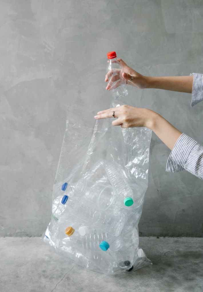 crop woman putting plastic bottle into bag